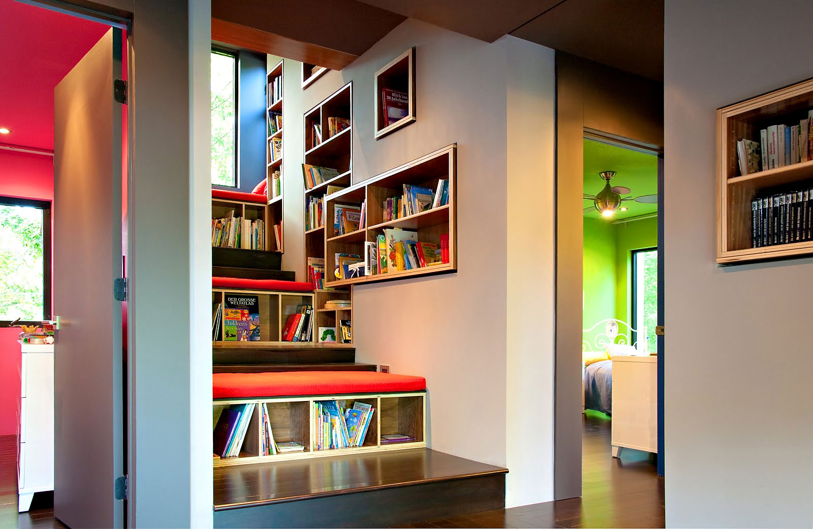 Creative home library with built in bookcases completed with tiered bookcases with red cushoins on top for sitting.jpg